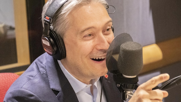 L'homme sourit et regarde Francis Reddy en entrevue.