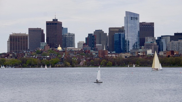un panoramique de la ville de Boston devant un étendue d'eau avec des voiliers