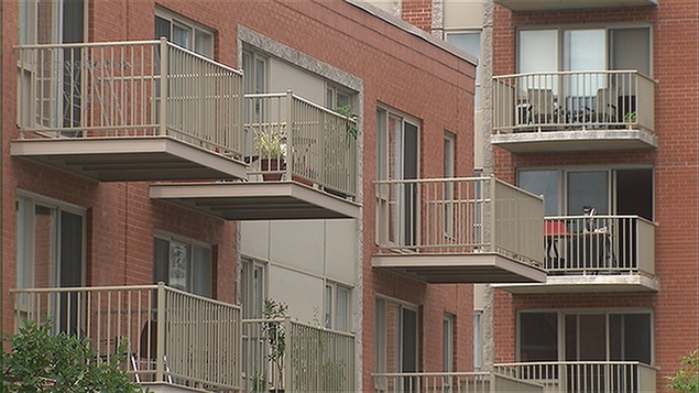 Vue sur des balcons d'un immeuble à condos avec des plantes et des chaises.