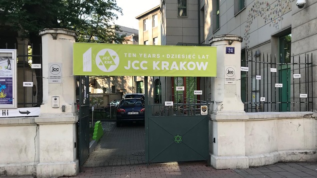 L'entrée d'une cour arrière d'un édifice avec une bannière sur lequel il est écrit les 10 ans du Centre communautaire juif de Cracovie