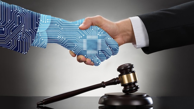 Un poignée de main, l'une artificielle et l'autre humaine au-dessus d'un maillet représentant la justice