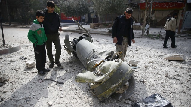 Des personnes examinent les restes d’un des nombreux missiles reçus sur la ville de Douma près de Damas en Syrie.