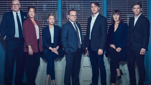 Les personnages principaux sont debout ou assis côte à côte.
