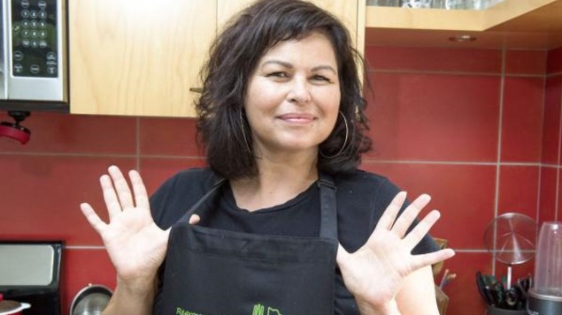 Dominique Pétin, porte-parole du Regroupement des popotes roulantes, portant un tablier, dans une cuisine
