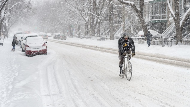 Un homme fait du vélo l'hiver à Montréal.