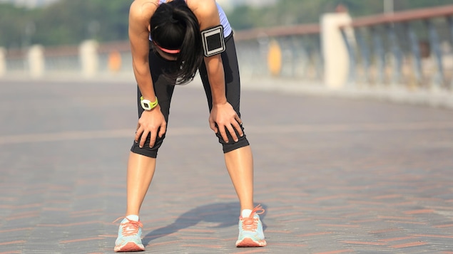 Une femme essoufflée court un marathon.