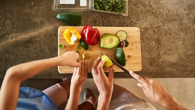 Un parent coupe des légumes avec son enfant.
