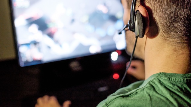 Un jeune homme joue à un jeu vidéo dans sa chambre.
