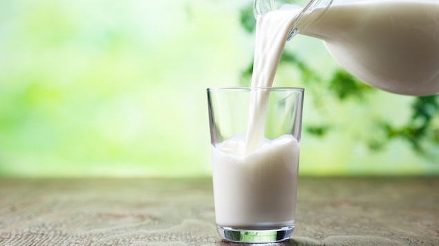 Une personne verse du lait dans un verre.