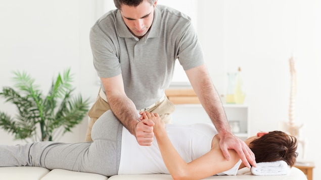 Un physiothérapeute s'exerce sur une patiente.