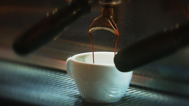 Tasse de café en céramique dans laquelle coulent deux minces filets d'espresso.
