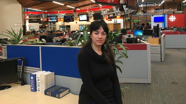 Une femme est photographiée dans une salle de nouvelles.