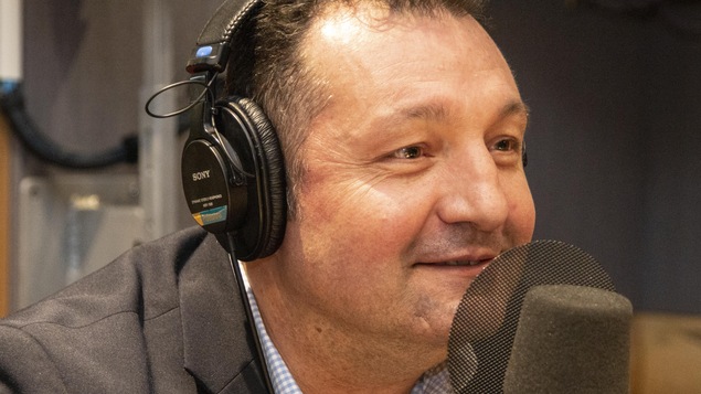 L'homme regarde l'animateur en souriant.