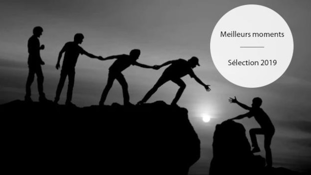 Un groupe de personne tendent la main afin d'aider une personne à gravir une montagne.