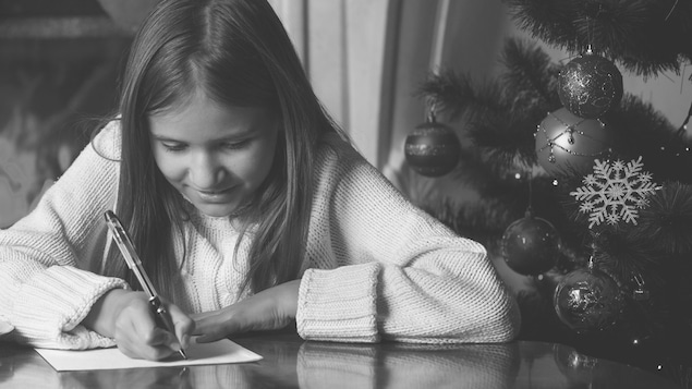 Une jeune fille écrit une lettre au père noël.