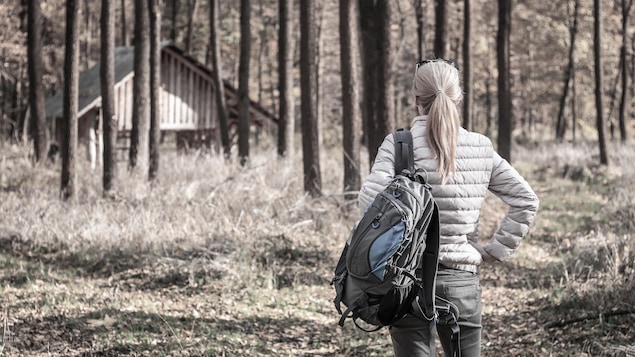 Une femme approche son refuge dans la forêt.