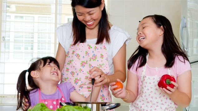 Une mère cuisine avec ses deux filles