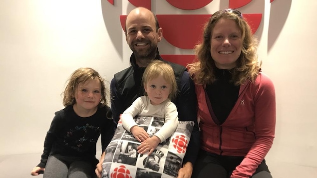 Un couple et leurs deux filles de 6 et 2 ans, assis devant un logo de Radio-Canada