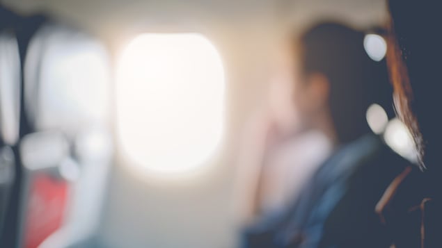 Un femme regarde à travers le hublot d'un avion.