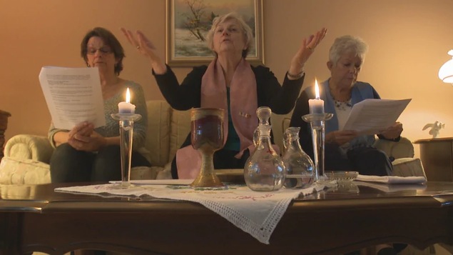 Tois femmes avec Marie Bouclin au centre célèbrent l'eucharistie