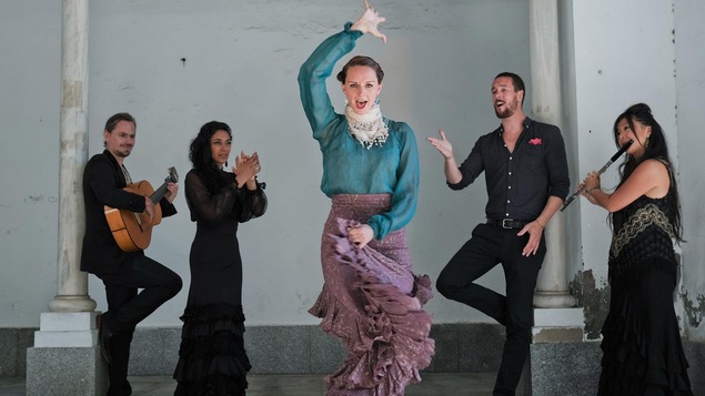 Une femme danse le flamenco pendant que quatre musiciens jouent derrière elle.