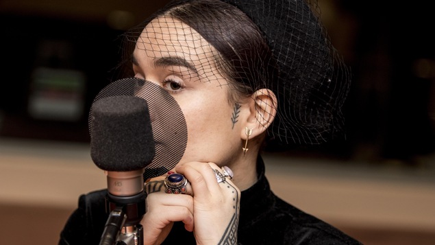 Elle porte un chapeau à filet, des bagues berbères, et une boucle d'oreille en forme de flèche.