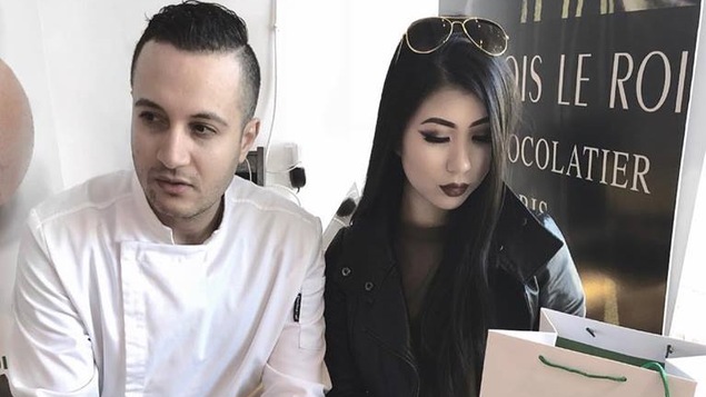 Le chocolatier et une jeune femme devant une affiche de sa boutique