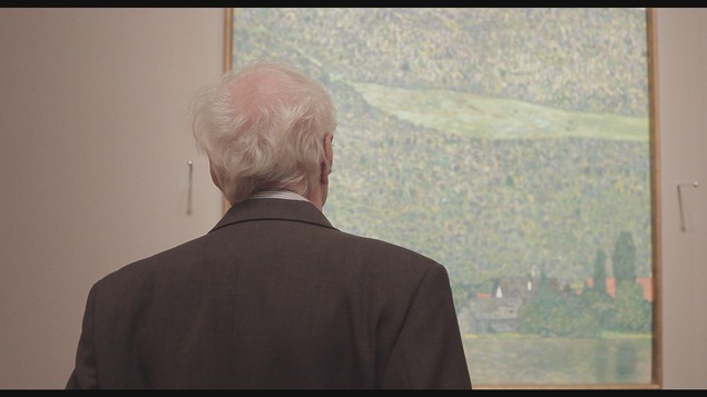Un homme est posé de dos et regarde un grand tableau d'un grand peintre