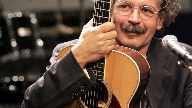 Gianmaria Testa tient sa guitare sur lui.