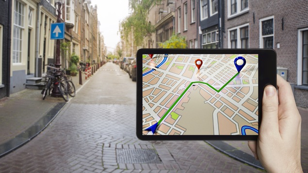 Une tablette affiche une application GPS dans un décor urbain.