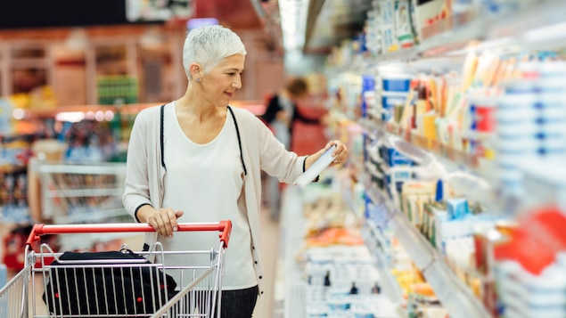 Femme regardant le tableau de valeur nutritive d'un aliment dans une épicerie
