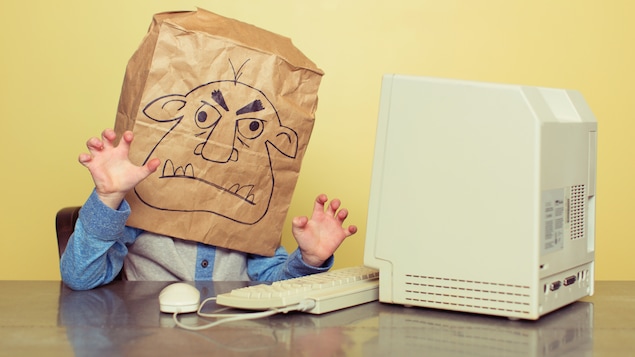 Un internaute se cache derrière son écran pour écrire des propos disgracieux à l'ère des réseaux sociaux.