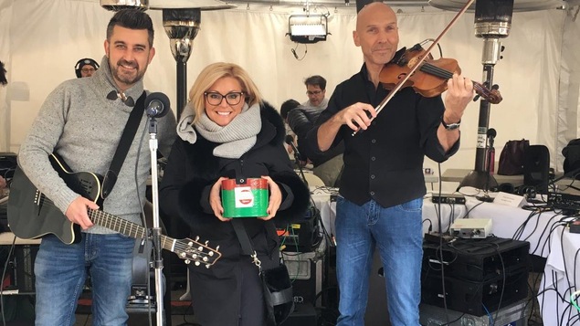 Un homme avec un guitare, une femme tenant une petite boîte et un homme tenant un violon.