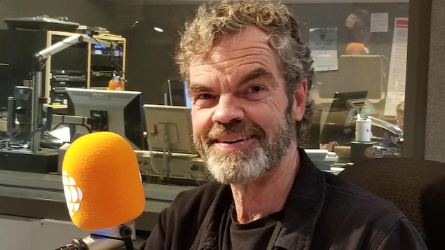 Edgar Bori sourit devant un micro dans un studio de Radio-Canada