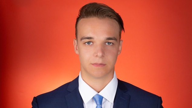 L'homme fixe l'objectif devant un fond orange-rouge