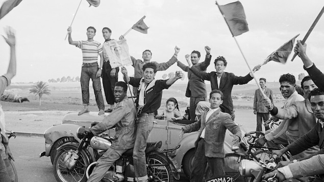 Des jeunes Marocains brandissent des drapeaux et lèvent les bras pour célébrer le retour du roi Mohammed V.