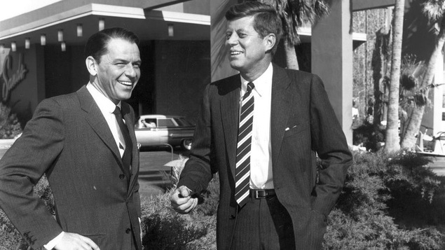 Photo en noir et blanc de deux hommes souriants sur une pelouse.