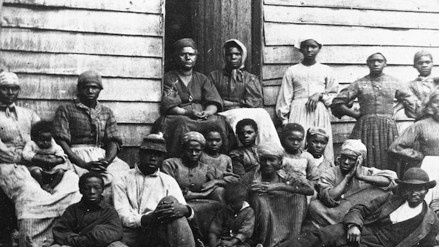 Des anciens esclaves posent devant un refuge temporaire à Arlington, en Virginie, au milieu des années 1860.