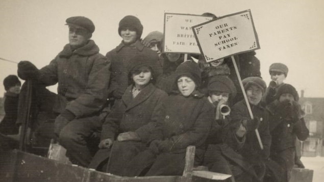 Des écoliers vêtus de manteaux tiennent des pancartes militantes.