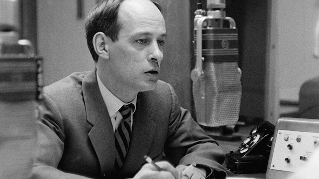 Dans un studio de radio, l'animateur René
Lévesque, une cigarette à la main, derrière
un micro suspendu.