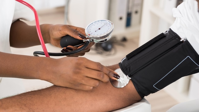 Un membre du personnel médical prend la tension d'un patient sur son bras.