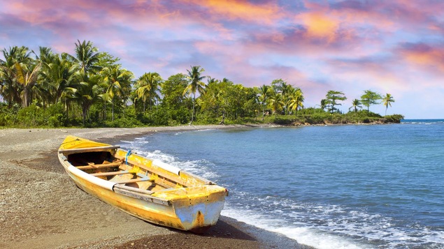 Une bateau de pêcheur traditionnel sur une plage au moment d'un couché de soleil.