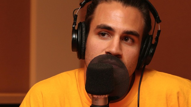 Jay Du Temple écoutant attentivement dans un studio de radio.