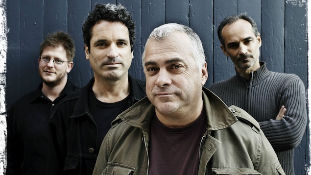 Pochette d'album du groupe Auguste, on y voit les 4 membres du groupe debout devant un mur.