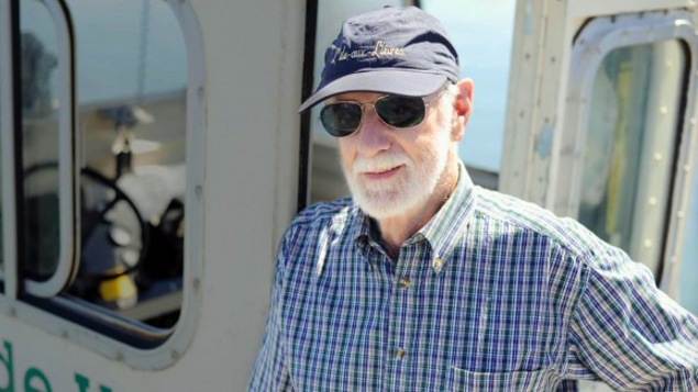 Un homme avec une casquette bleue et des lunettes de soleil est sur un bateau.