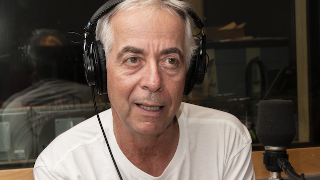 L'homme a un casque sur les oreilles en entrevue dans un studio de radio.