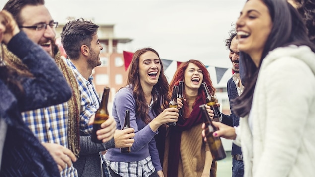Des jeunes adultes consomment de la bière en bouteille.