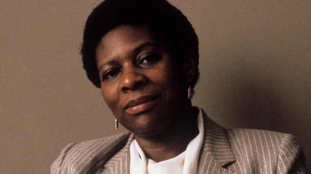 Juanita Westmoreland-Traoré souriant devant un mur beige.