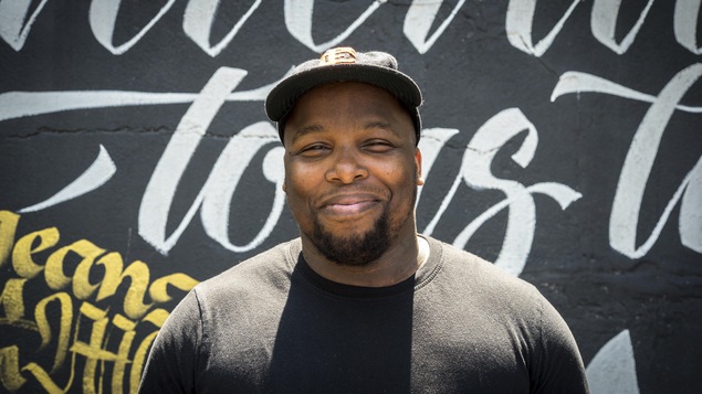 Kenny Thomas devant un mur couvert de graffitis