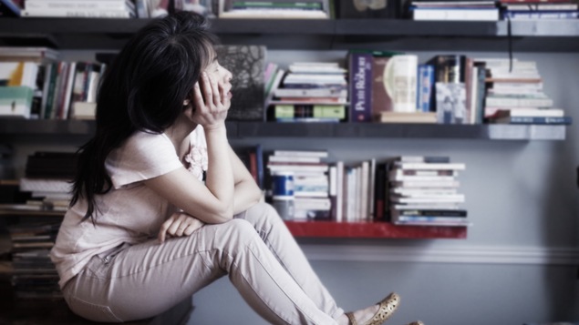 Kim Thuy réfléchit devant une bibliothèque